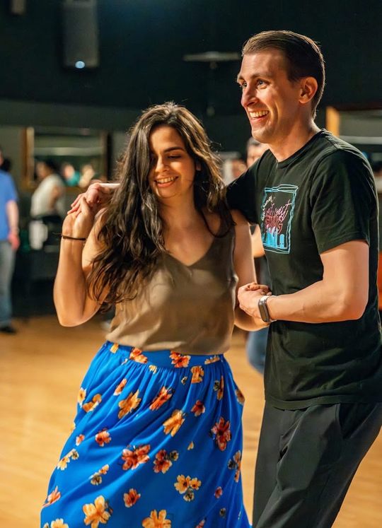 Ben dancing with a partner in a blue floral skirt